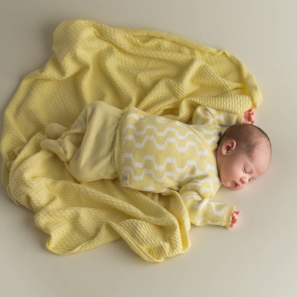 Gelbe Babydecke aus Bio-Baumwolle mit Baby-Flatlay